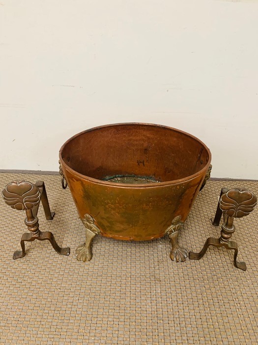 A large coal bin in copper with lion handles and claw feet and a pair of copper fire dogs