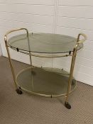 Brass plated drinks trolley, oval shape with smoked glass (H63cm W63cm D46cm)