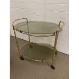 Brass plated drinks trolley, oval shape with smoked glass (H63cm W63cm D46cm)