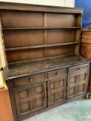 An oak style dresser with open rack over three drawers and three cupboards