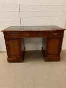 A mahogany pedestal desk flanked with cupboards and green leather top