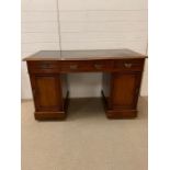 A mahogany pedestal desk flanked with cupboards and green leather top