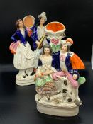 Two Staffordshire figural groups, one couple holding musical instruments, one couple sat with