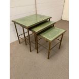 A brass nest of tables on reed legs with glass tops.