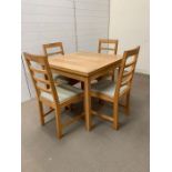 An oak dining/kitchen table with extending sides and four chairs