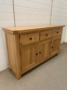 An oak sideboard with three drawers and cupboards below (H86cm W147cm D40cm)