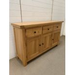 An oak sideboard with three drawers and cupboards below (H86cm W147cm D40cm)