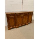 A Yew wood sideboard with double doors to centre flanked by single cupboards and three drawers H87cm