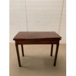 A mahogany fold over tea table supported by square moulded legs.