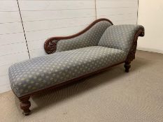 A chaise longue with padded seat and scrolled ends