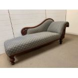 A chaise longue with padded seat and scrolled ends