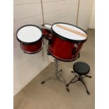 A red children's drum kit with stool
