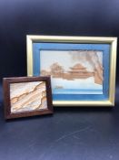 A framed 3D picture of a sea and mountain scenery and a framed miniature of the mountains