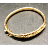 A yellow gold bangle with safety chain marked 15 ct (13.2g)