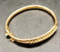 A yellow gold bangle with safety chain marked 15 ct (13.2g)