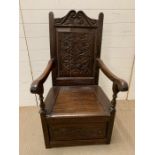 A 17th century style carved oak panel back armchair with box seat