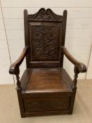 A 17th century style carved oak panel back armchair with box seat
