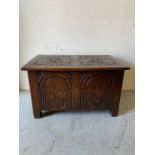 An oak carved coffer with hinged top paneled side and front (H48cm D49cm W80cm)