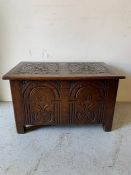 An oak carved coffer with hinged top paneled side and front (H48cm D49cm W80cm)