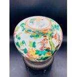 A Chinese porcelain jar and cover decorated with birds and flowers sitting on a stand.