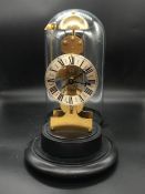 A Kieninger Skeleton Bell Chime Clock under a glass dome.