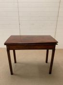 A mahogany fold over tea table supported by square moulded legs.