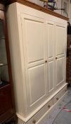 A large cream painted solid pine double wardrobe with hanging rails and two drawers under