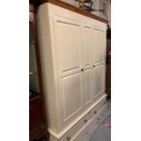 A large cream painted solid pine double wardrobe with hanging rails and two drawers under