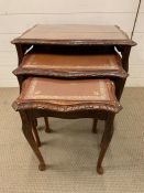 A nest of three glass top tables with leather tops