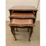 A nest of three glass top tables with leather tops