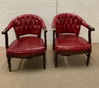 A pair of red leather library arm chairs, upholstered button back on oak tub frame