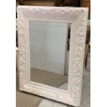 A carved painted wall mirror with a floral border