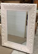 A carved painted wall mirror with a floral border