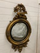 A Regency oval convex mirror in a gilt frame with reclining deer, with silvered finish, original