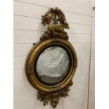 A Regency oval convex mirror in a gilt frame with reclining deer, with silvered finish, original