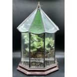 A stained glass terrarium on wooden stand