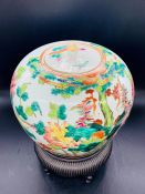 A Chinese porcelain jar and cover decorated with birds and flowers sitting on a stand.