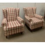 A pair of wing back arm chairs with red check upholstery