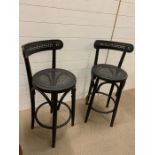 A pair of bar stools with cane back and seat