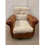 An armchair with leather arms and sides and oak back frame with separate upholstered cushions