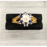 An 18 ct yellow gold Daisy style ring with central diamond and six sapphires (4.2g)