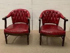 A pair of red leather library arm chairs, upholstered button back on oak tub frame