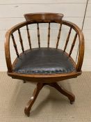 An oak swivel office chair with turned spindle back and leather seat pad