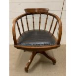 An oak swivel office chair with turned spindle back and leather seat pad