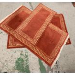 Three red rugs with geometric borders of various sizes