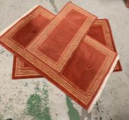 Three red rugs with geometric borders of various sizes