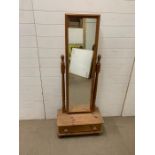 A pine free standing mirror on drawer base and bun feet