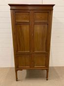 A mahogany cabinet on legs with inlaid detail