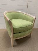 A tub chair with green upholstery and solid wood frame