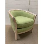 A tub chair with green upholstery and solid wood frame